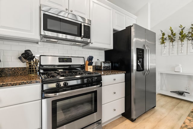 kitchen featuring white cabinets, dark stone counters, stainless steel appliances, and light hardwood / wood-style floors