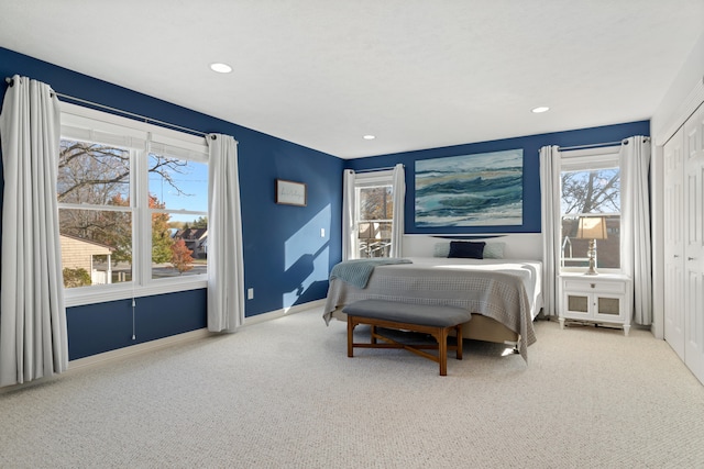 bedroom with multiple windows, a closet, and light colored carpet