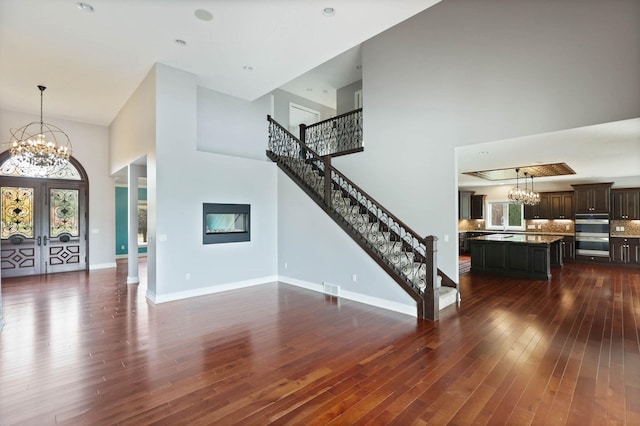 living room featuring a high ceiling, dark hardwood / wood-style floors, an inviting chandelier, and french doors