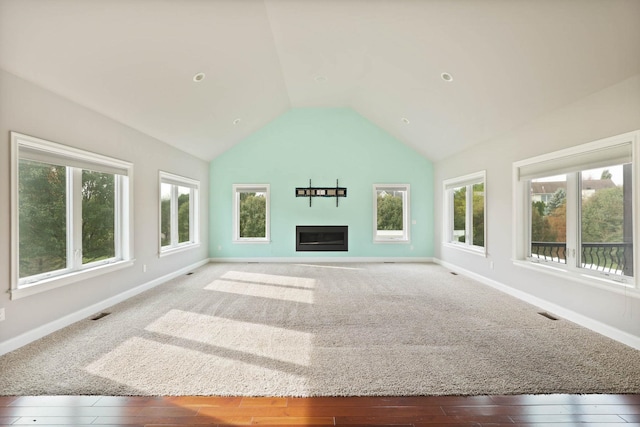 unfurnished living room with a wealth of natural light, high vaulted ceiling, and hardwood / wood-style flooring