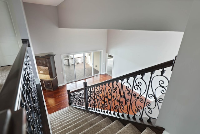 stairway with a towering ceiling and hardwood / wood-style flooring