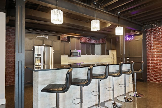 kitchen with a breakfast bar area, decorative light fixtures, stainless steel appliances, and brick wall