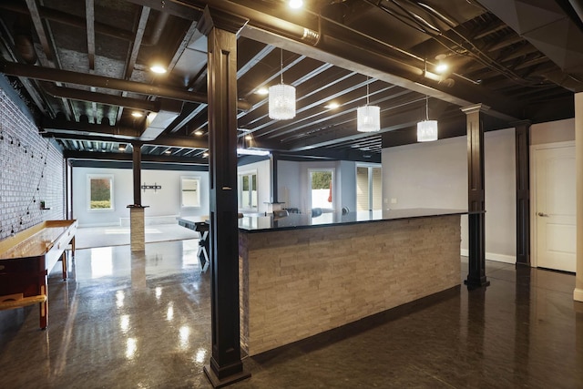 kitchen with pendant lighting, ornate columns, and brick wall