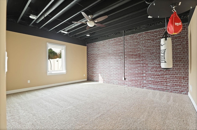 spare room featuring ceiling fan, carpet, and brick wall