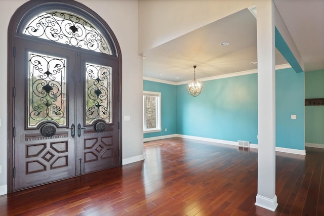 entrance foyer with an inviting chandelier, dark hardwood / wood-style flooring, ornamental molding, and french doors