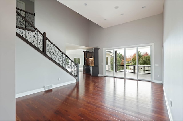 unfurnished living room featuring dark wood-type flooring and a high ceiling