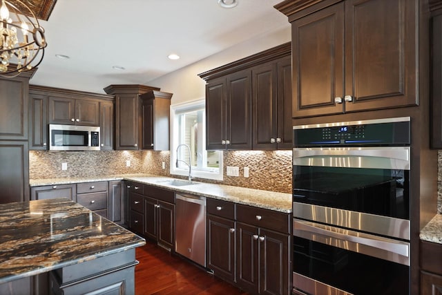 kitchen with decorative backsplash, dark stone counters, stainless steel appliances, sink, and dark hardwood / wood-style floors