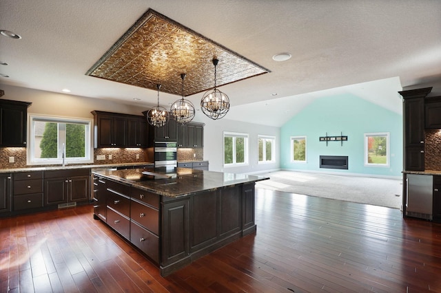 kitchen with tasteful backsplash, a wealth of natural light, a kitchen island, and vaulted ceiling