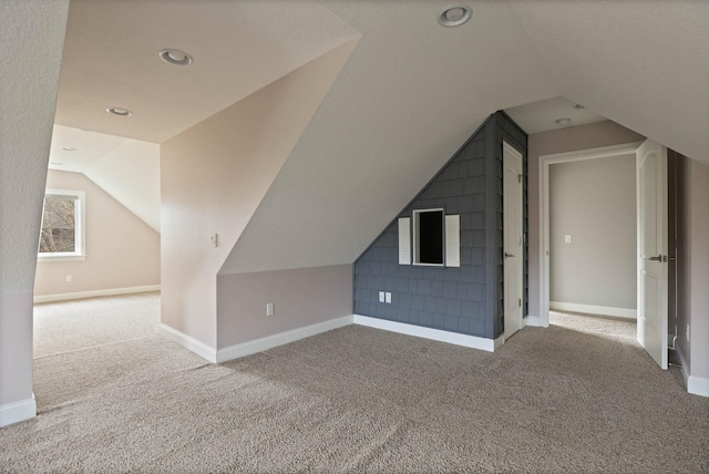 additional living space featuring light carpet, a textured ceiling, and lofted ceiling