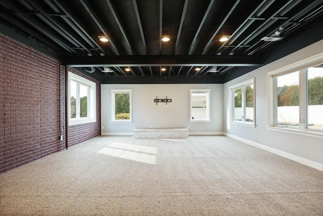 carpeted empty room with a wealth of natural light and brick wall