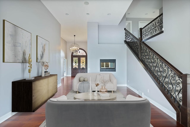 living room with french doors, dark wood-type flooring, a high ceiling, and an inviting chandelier