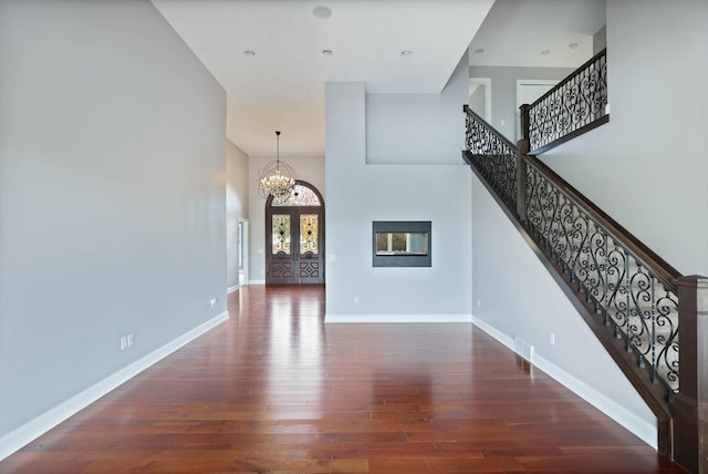 entryway with french doors, a towering ceiling, an inviting chandelier, and dark hardwood / wood-style flooring