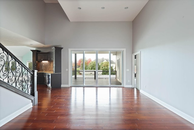 unfurnished living room with dark hardwood / wood-style flooring and a towering ceiling