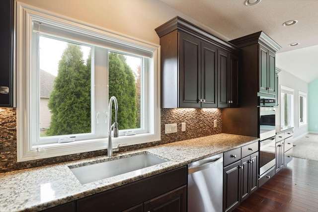 kitchen with dishwasher, sink, dark hardwood / wood-style floors, light stone countertops, and dark brown cabinets