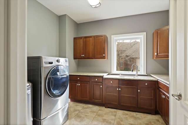 laundry room featuring sink, light tile patterned flooring, and cabinets