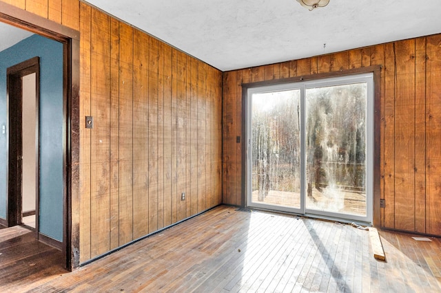 spare room with hardwood / wood-style floors and wood walls