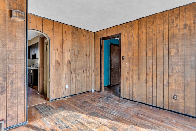 unfurnished room featuring wood walls and dark wood-type flooring