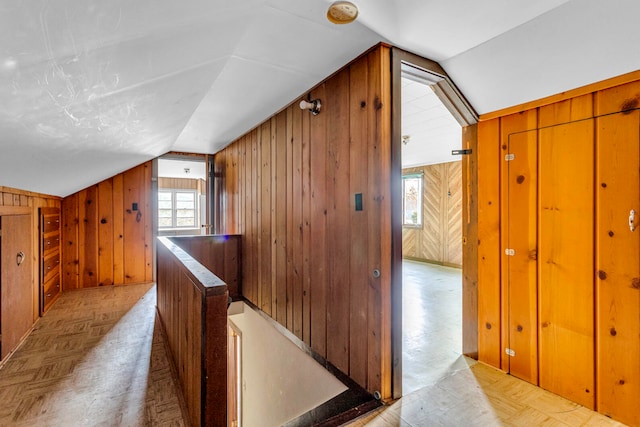 bonus room with light parquet floors, lofted ceiling, and wood walls