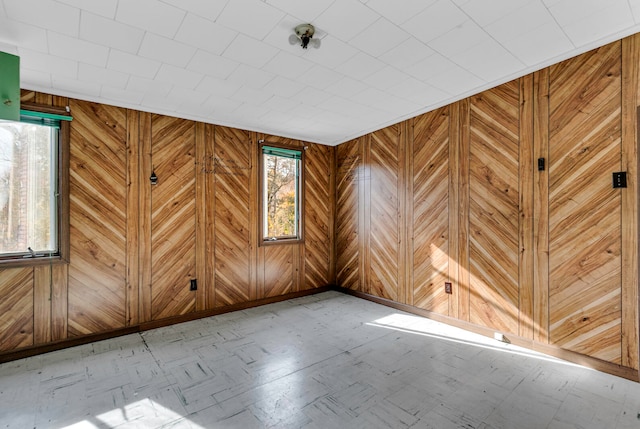 unfurnished room featuring wooden walls and plenty of natural light