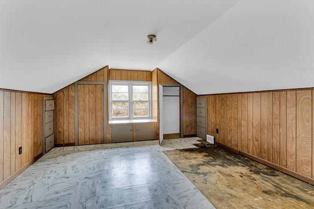 bonus room featuring vaulted ceiling and wood walls