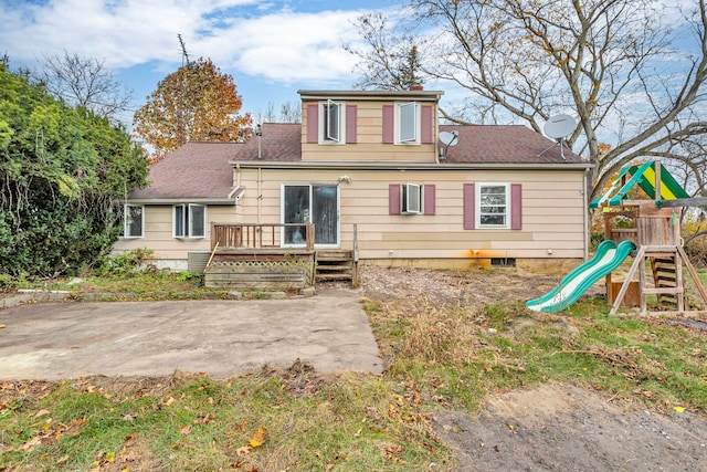 back of property featuring a playground and a deck