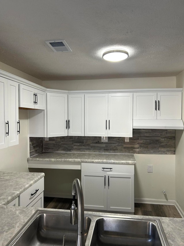 kitchen with a textured ceiling, white cabinetry, sink, and dark hardwood / wood-style floors