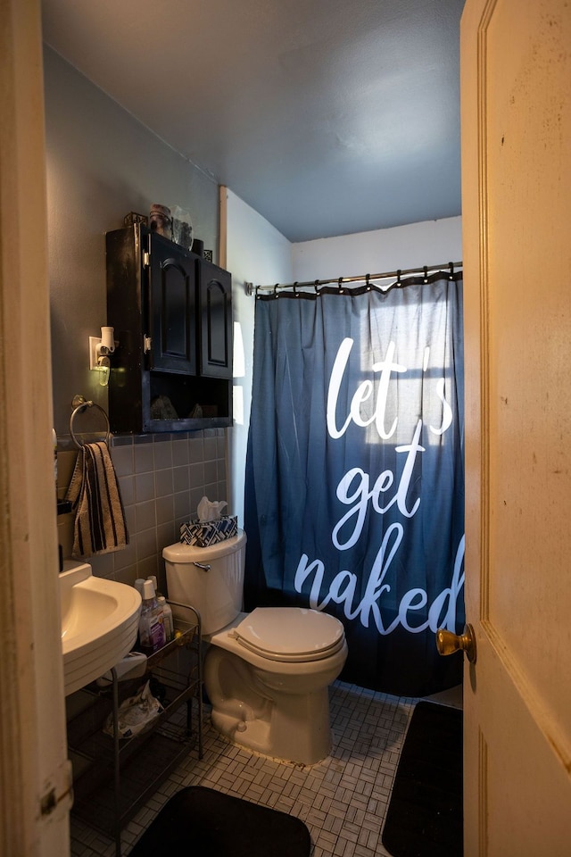 bathroom featuring sink, a shower with curtain, tile patterned flooring, toilet, and tile walls