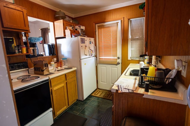 kitchen with wood walls, dark tile patterned flooring, and white appliances