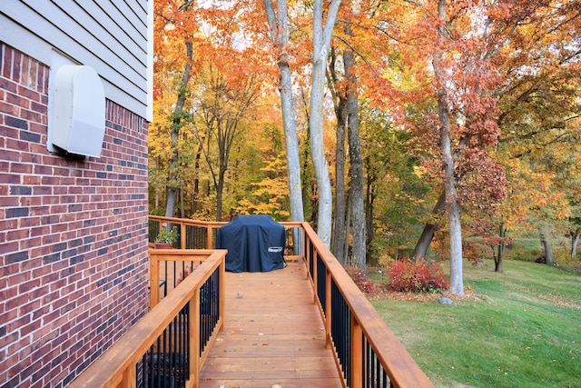 wooden terrace featuring area for grilling and a yard