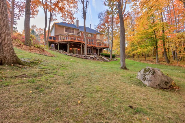 rear view of house featuring a lawn and a wooden deck