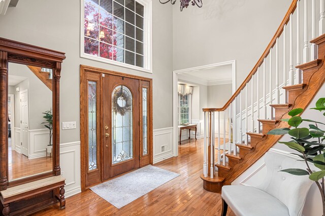 foyer entrance with a high ceiling, crown molding, a notable chandelier, and wood-type flooring