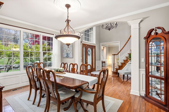 dining room featuring decorative columns, crown molding, a notable chandelier, and light wood-type flooring