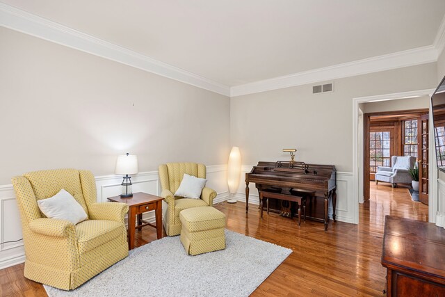 sitting room with wood-type flooring and ornamental molding