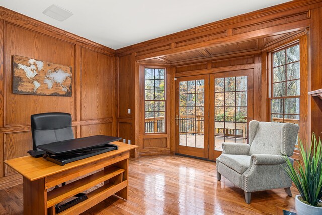 office area with wooden walls, light wood-type flooring, and a wealth of natural light