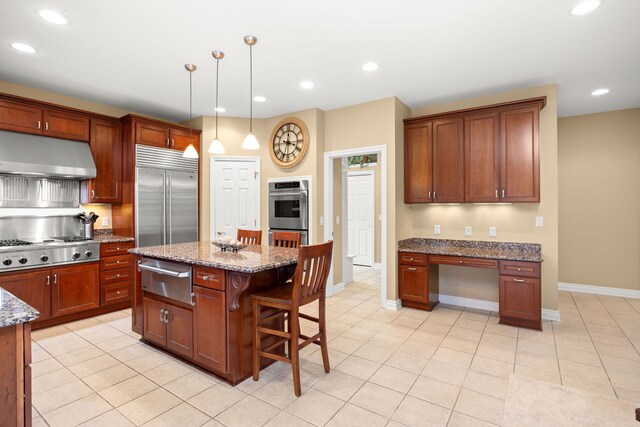 kitchen with light stone counters, a breakfast bar, stainless steel appliances, decorative light fixtures, and a center island