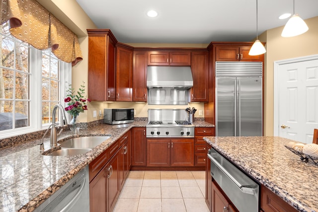 kitchen with light stone countertops, stainless steel appliances, sink, light tile patterned floors, and hanging light fixtures