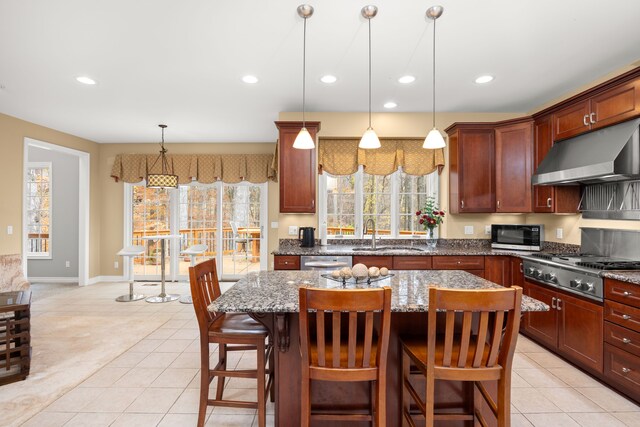 kitchen with sink, hanging light fixtures, stainless steel appliances, dark stone counters, and a kitchen island