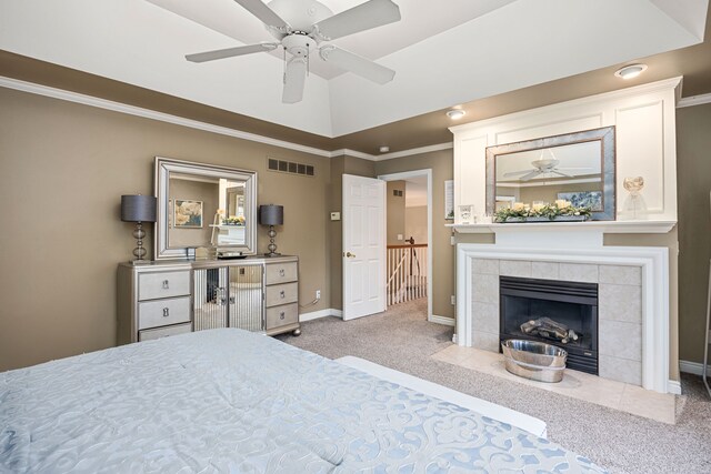 bedroom with a tile fireplace, light colored carpet, ceiling fan, and ornamental molding