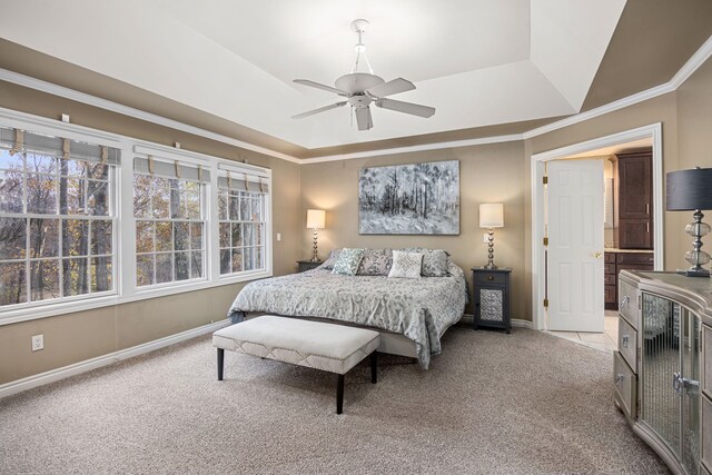 bedroom with connected bathroom, ceiling fan, crown molding, a tray ceiling, and light carpet