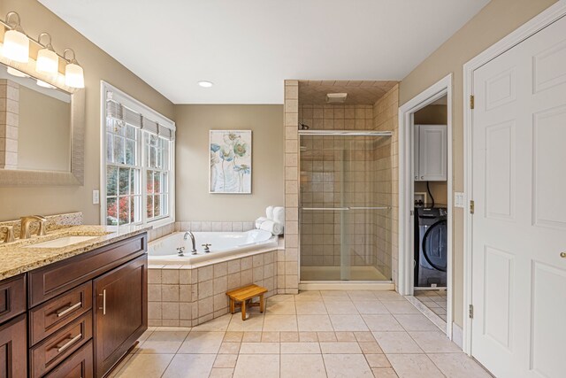 bathroom featuring tile patterned floors, vanity, independent shower and bath, and washer / dryer