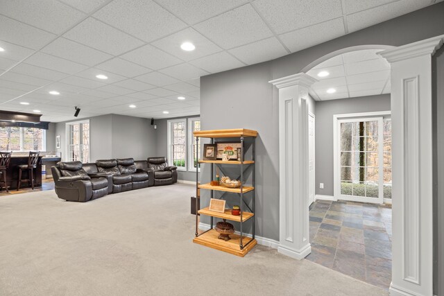 living room with decorative columns, carpet flooring, a drop ceiling, and indoor bar