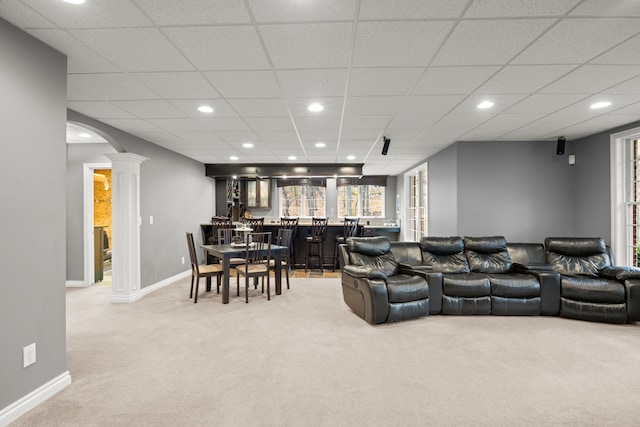 carpeted living room featuring a paneled ceiling and ornate columns