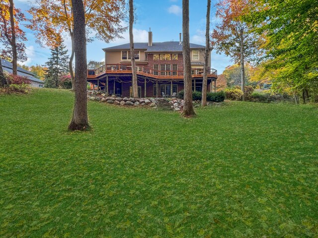 rear view of house featuring a deck and a lawn