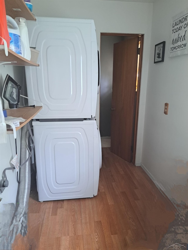 clothes washing area with wood-type flooring and stacked washing maching and dryer