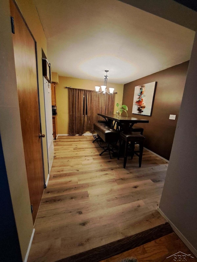 dining room with light hardwood / wood-style flooring and a notable chandelier