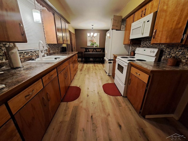 kitchen with white appliances, sink, light hardwood / wood-style flooring, a notable chandelier, and hanging light fixtures