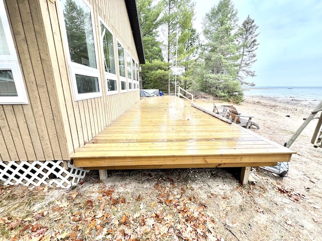 wooden deck featuring a beach view and a water view