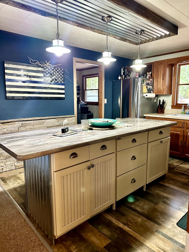 kitchen featuring stainless steel refrigerator, a center island, hanging light fixtures, dark wood-type flooring, and cream cabinetry