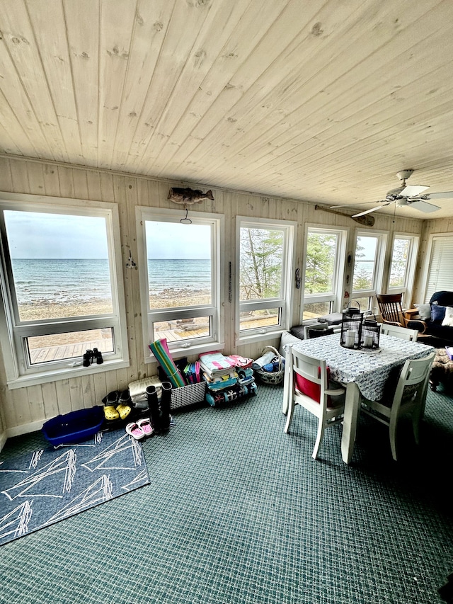 sunroom with a beach view, a water view, ceiling fan, and wooden ceiling