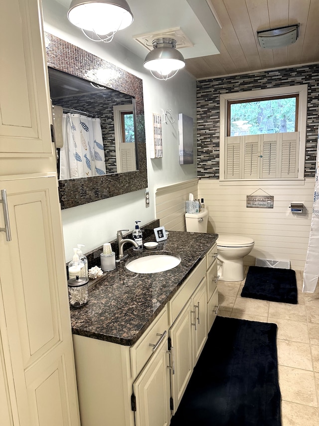 bathroom featuring tile patterned floors, vanity, wood walls, and toilet